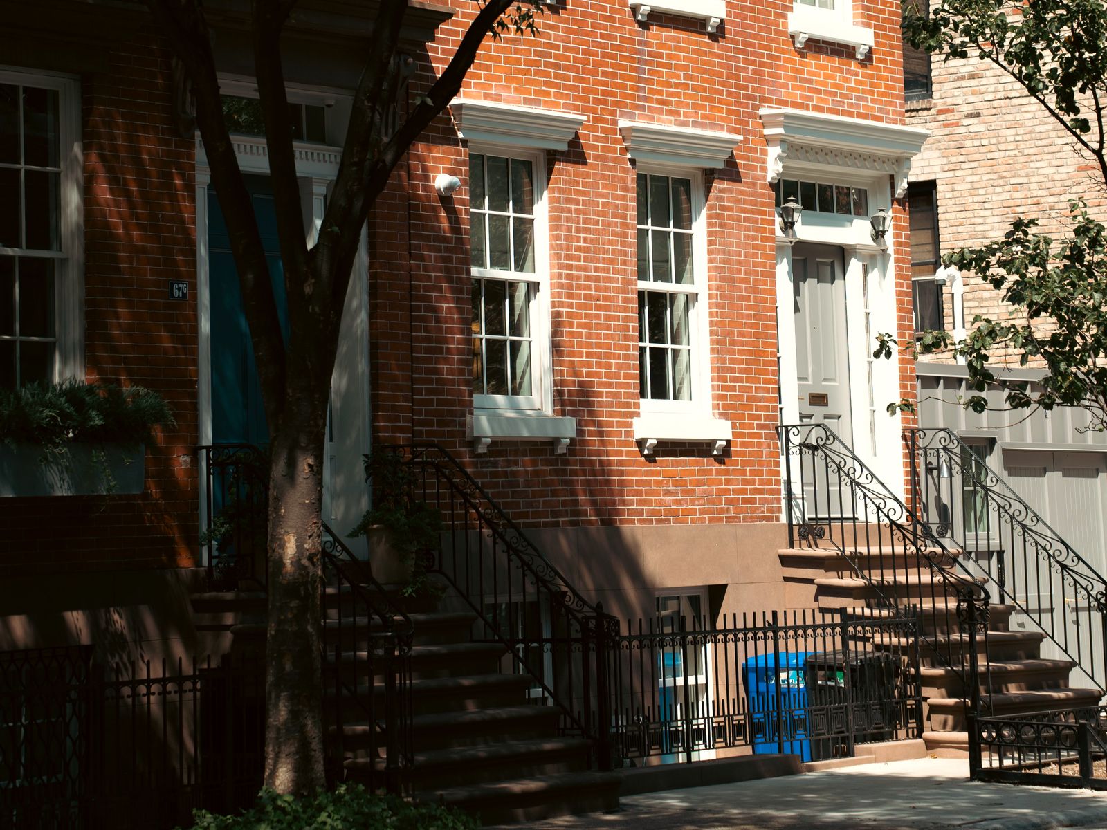 Brick brownstone facade shaded by street trees